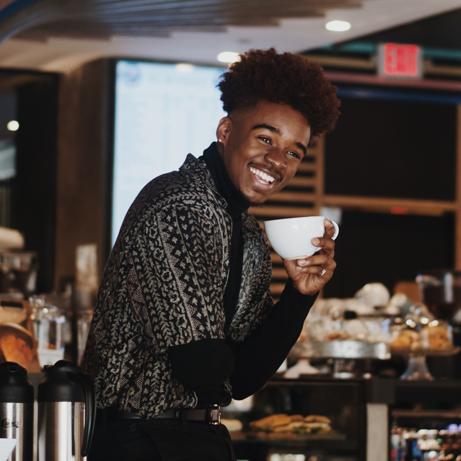 male model posing in coffee shop a mug in hand